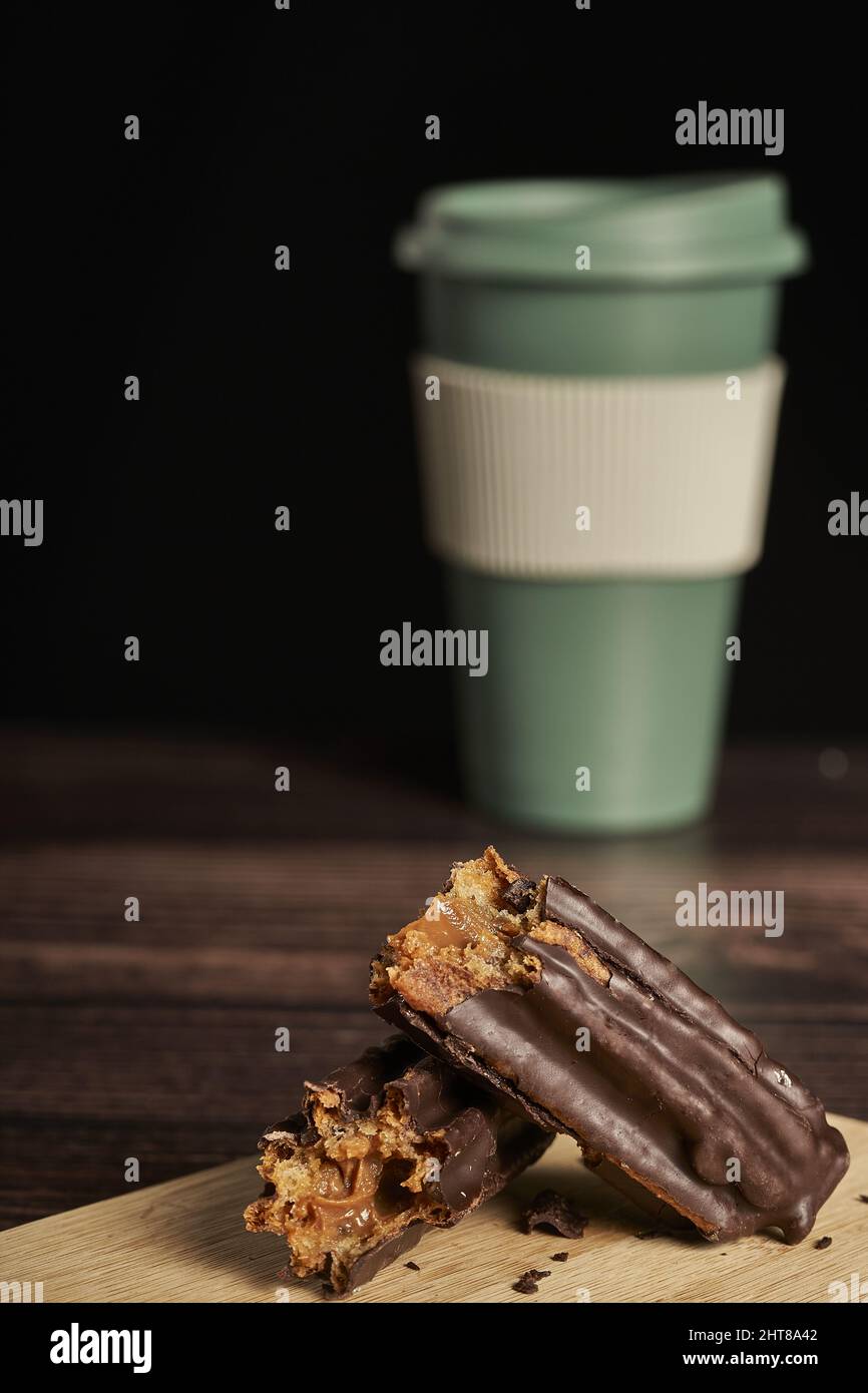 Un primo colpo di un churro riempito e immerso nel cioccolato e una tazza di caffè sullo sfondo Foto Stock