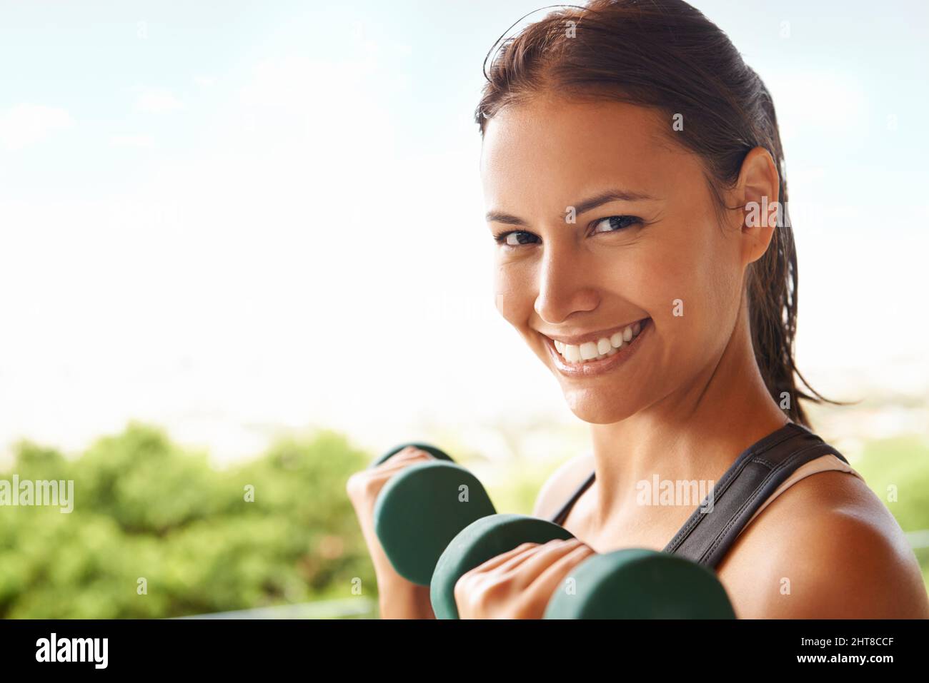Mi piace il mio allenamento con il peso. Ritratto di una giovane donna sportiva che si allena con manubri. Foto Stock