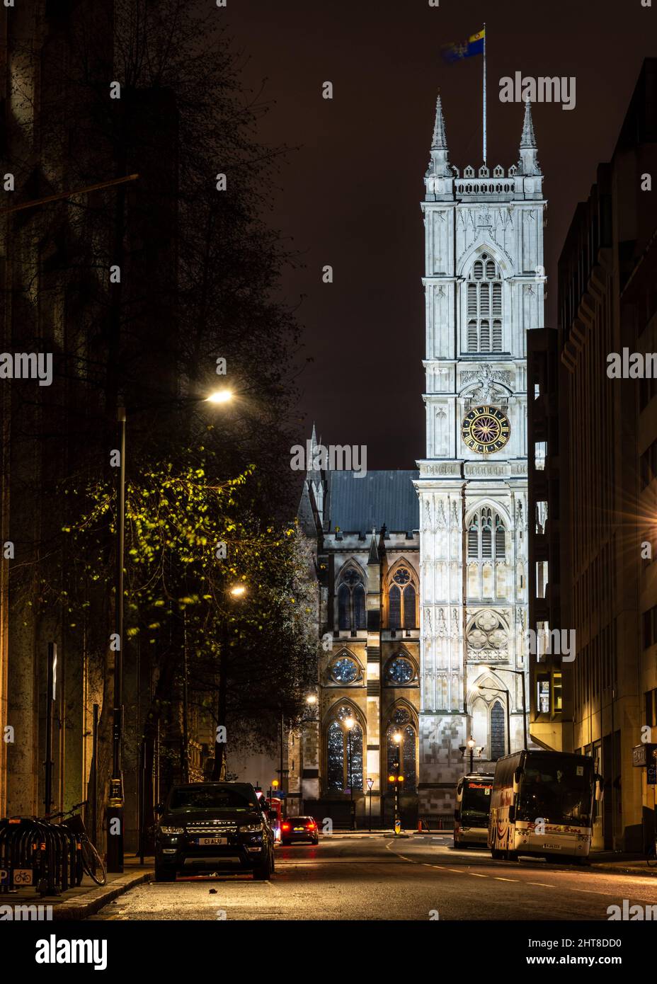 Il lato ovest e le torri dell'abbazia di Westminster sono illuminate di notte come si intravede tra gli edifici di uffici di Londra. Foto Stock