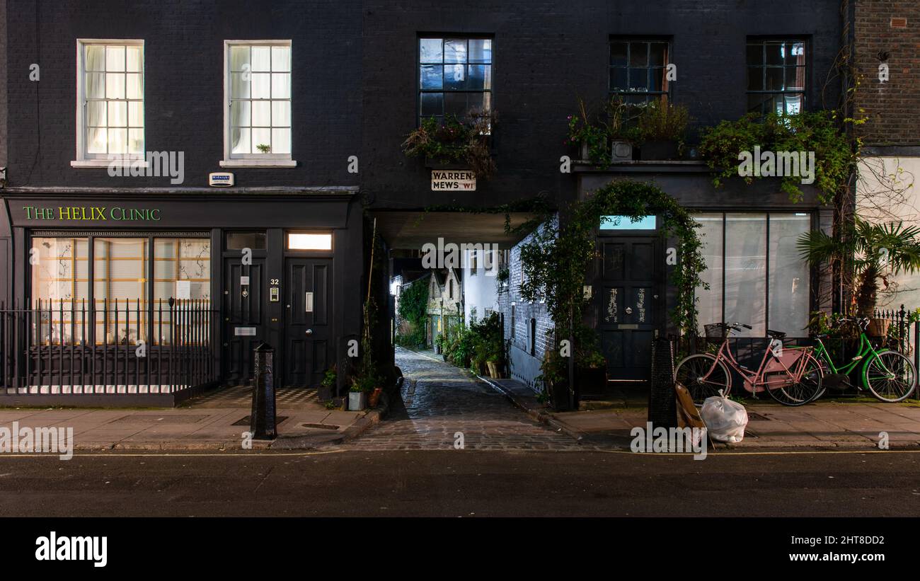 Le case di Mews si intravedono attraverso un arco sotto le case cittadine di Warren Street, nella città di Westminster a Londra. Foto Stock