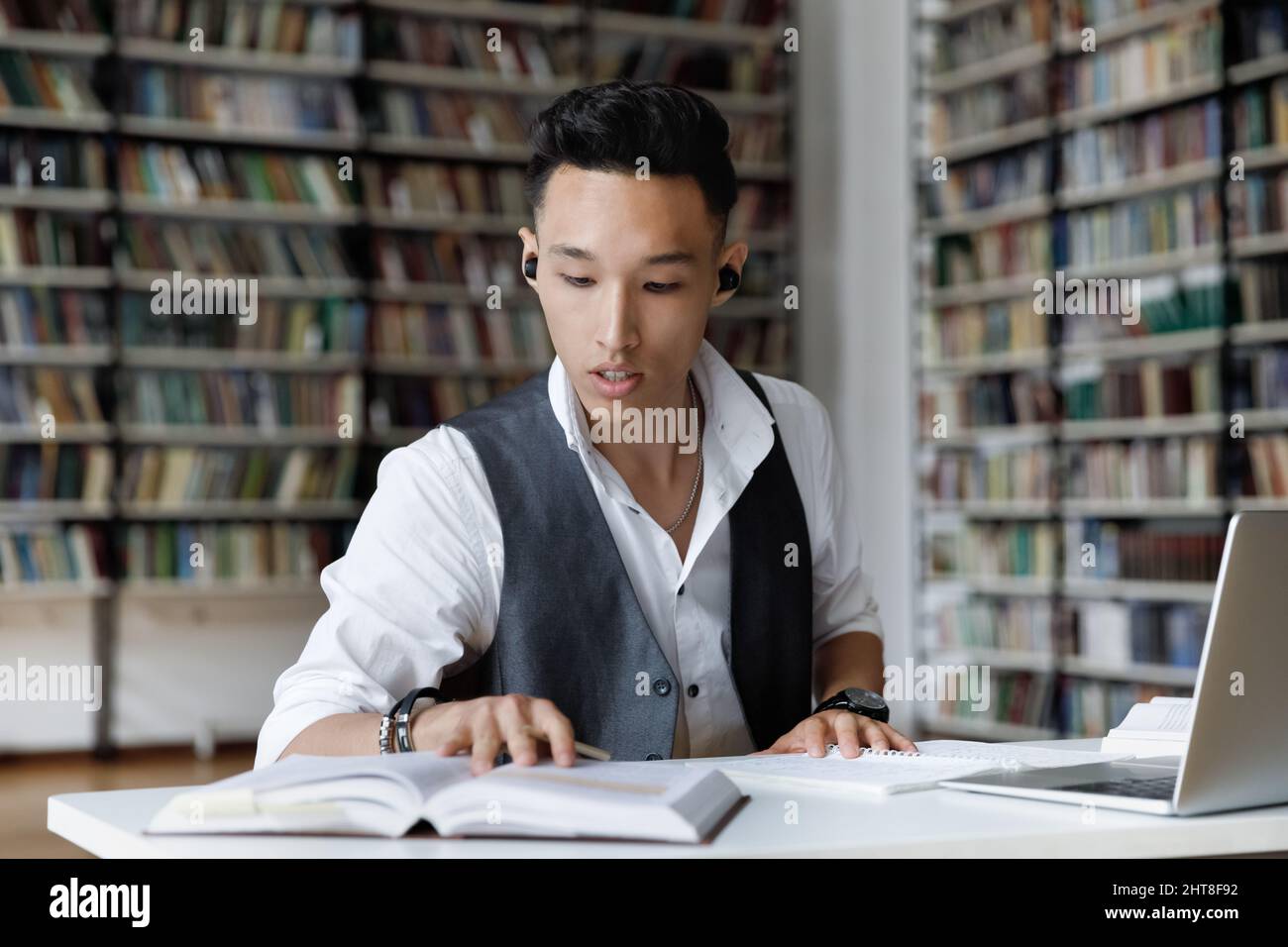 Concentrato millenario studente coreano maschio apprendimento in biblioteca. Foto Stock