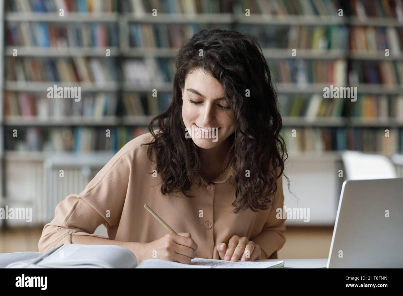 Felice giovane ispanica che studia in biblioteca. Foto Stock