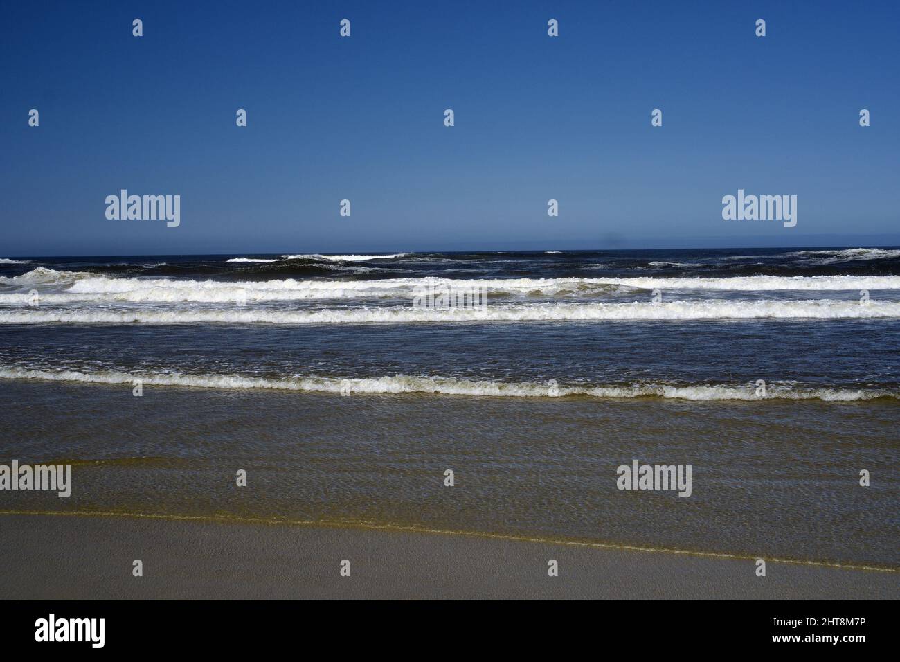 Un bel mare con le onde che colpiscono la riva in una giornata di sole Foto Stock