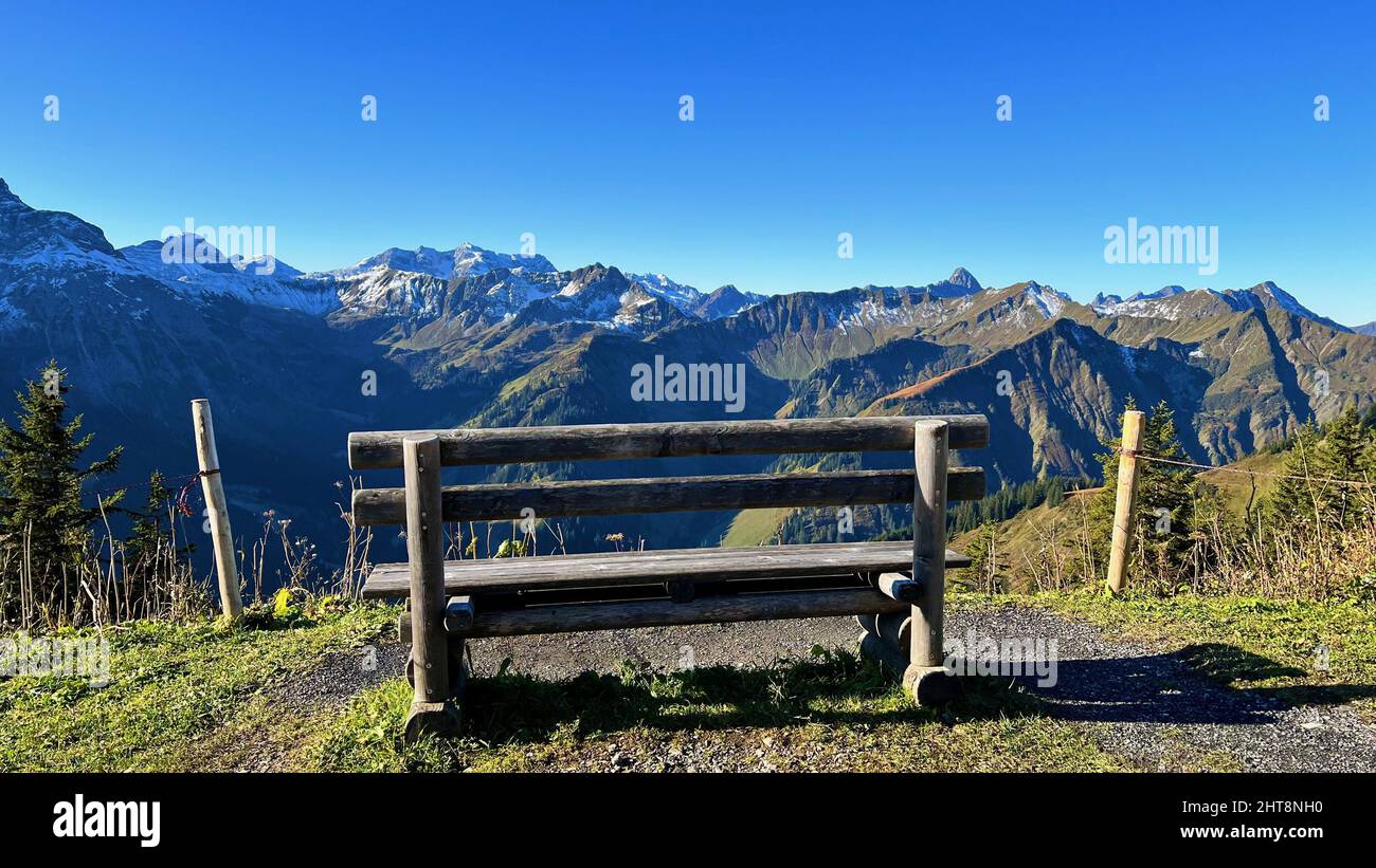 Un'unica panchina sul bordo di un canyon con la vista delle montagne contro un cielo senza nuvole Foto Stock