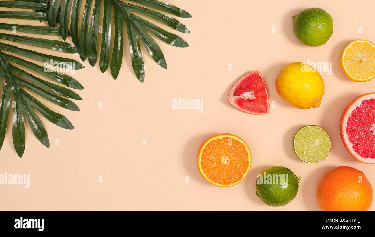Sfondo estivo con agrumi tropicali estivi e foglie di palma verdi naturali a tema beige. Disposizione piatta Foto Stock