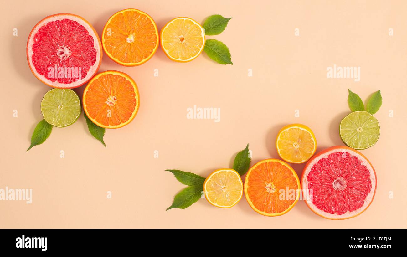 Layout creativo con spazio copia e agrumi tropicali estivi e foglie verdi naturali su sfondo beige. Disposizione piatta Foto Stock