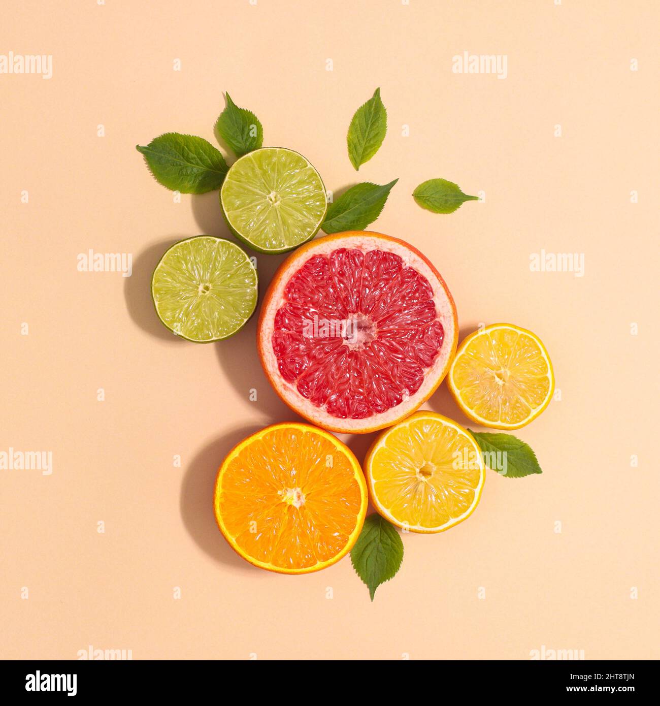 Layout creativo con agrumi tropicali estivi e foglie verdi naturali su sfondo beige. Disposizione piatta Foto Stock