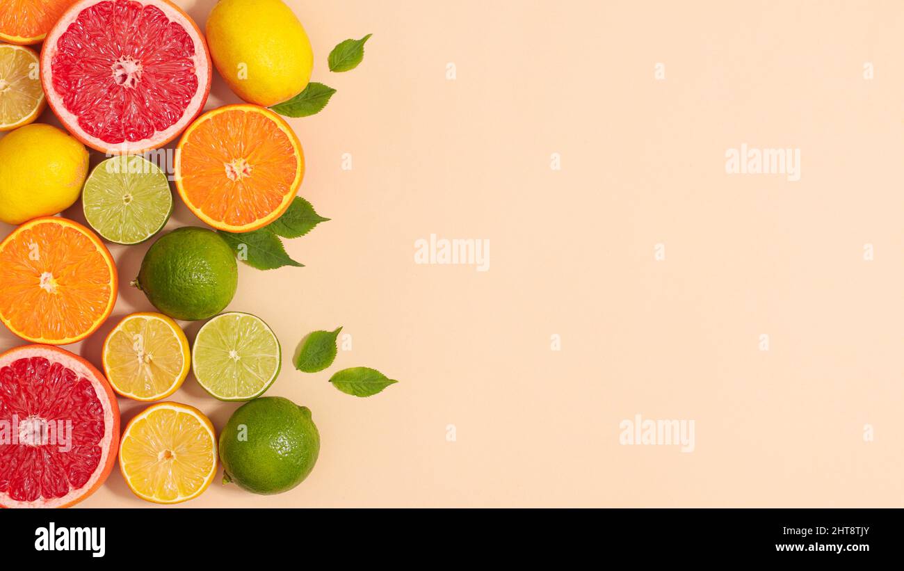 Spazio creativo di fondo copia con agrumi tropicali estivi e foglie verdi naturali a tema beige. Disposizione piatta Foto Stock