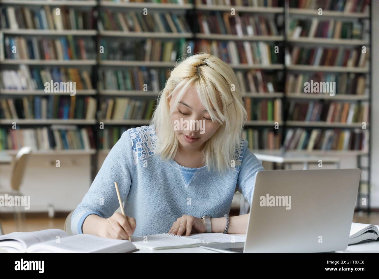 Donna asiatica concentrata e intelligente che studia in biblioteca. Foto Stock