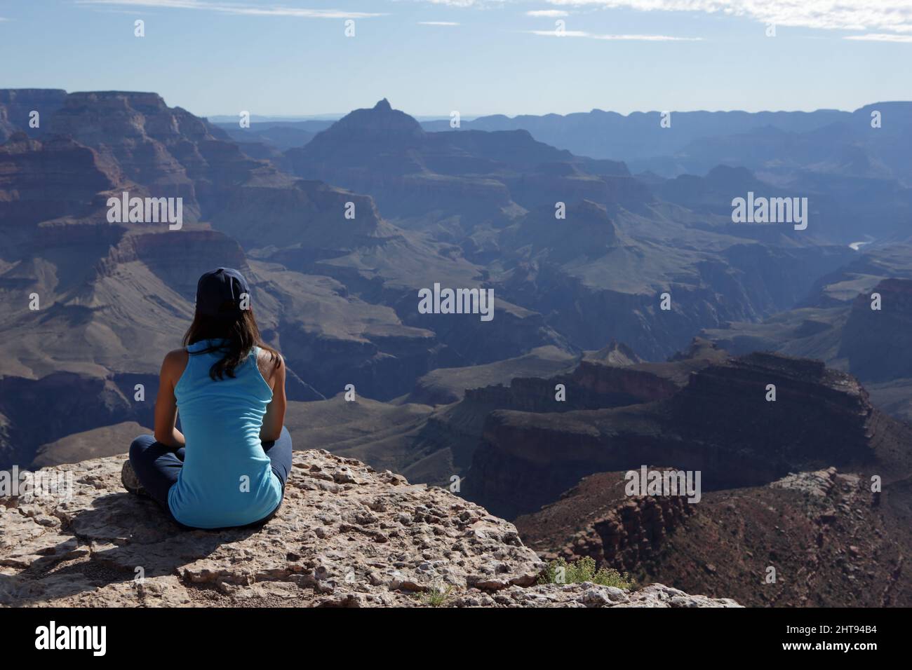 Una ragazza si siede a gambe incrociate e guarda la vista di scogliere, buttes, e strati di roccia, nelle profondità del Grand Canyon a Shoshone Point sul Sou Foto Stock