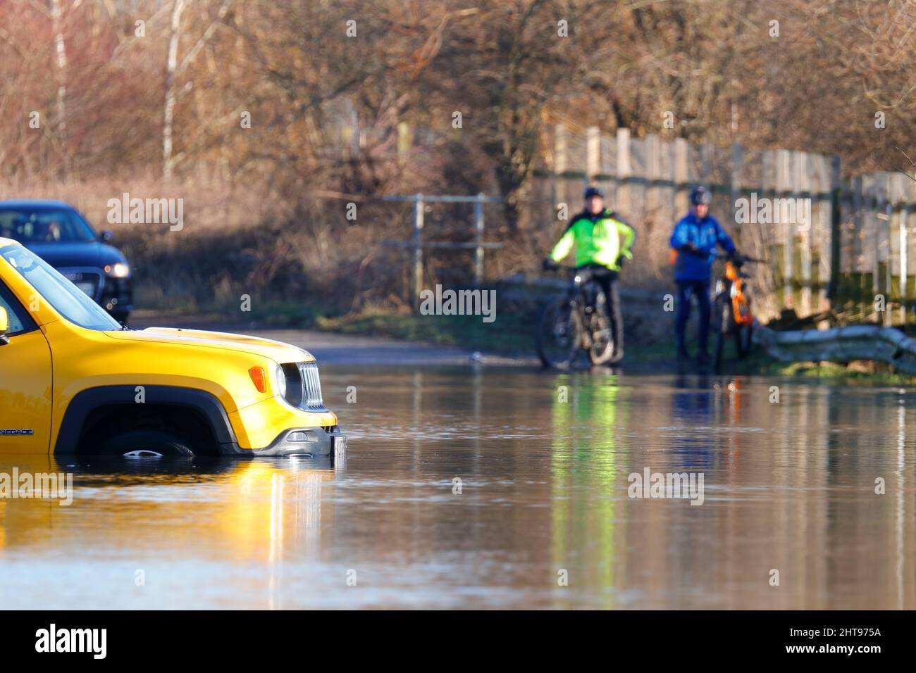I ciclisti guardano avanti mentre un veicolo è rimasto intrappolato in acqua su Newton Lane vicino Castleford, dopo che Storm Franklin ha portato alluvione in molte parti del Regno Unito Foto Stock