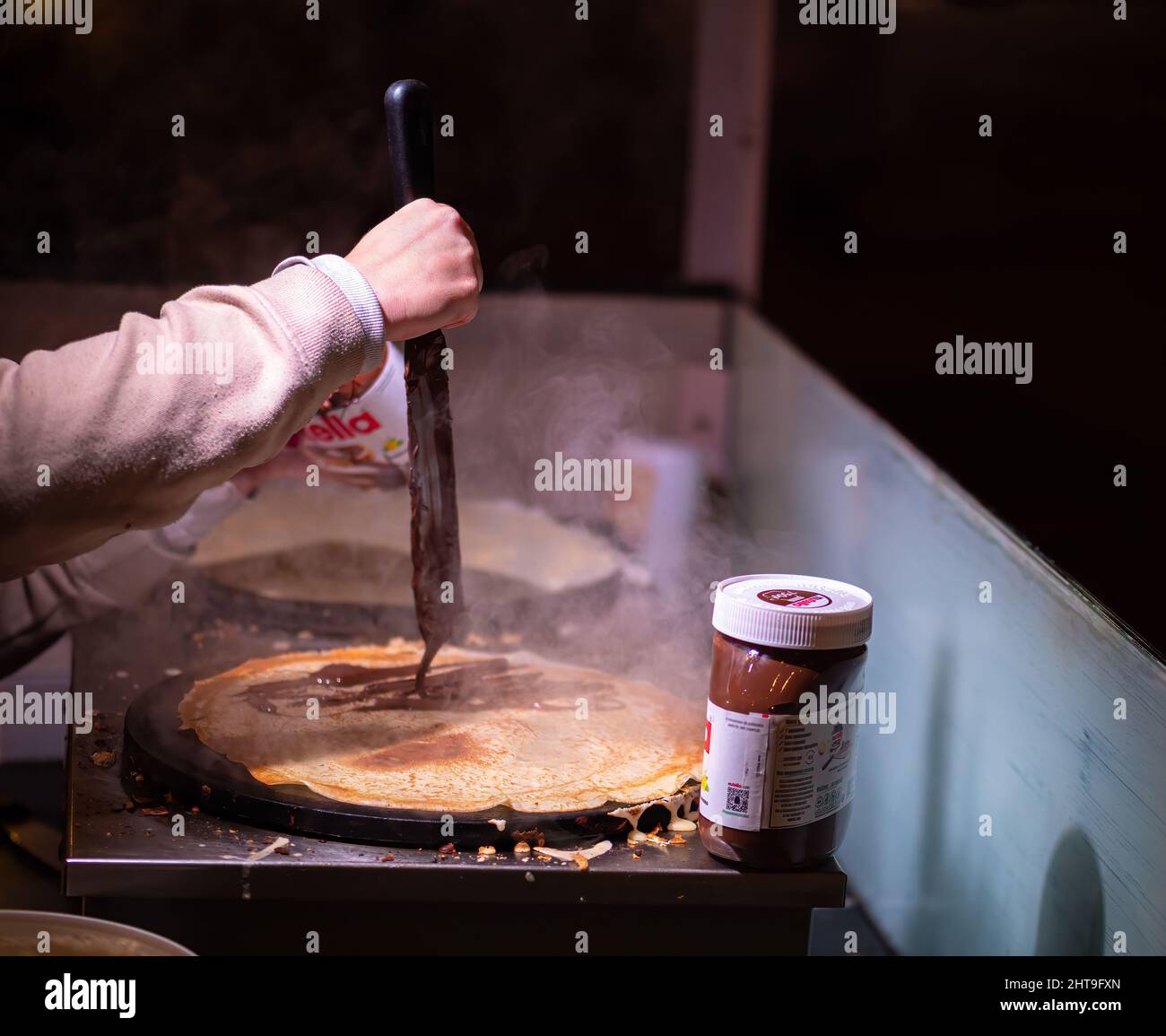 Colmar, Francia - 13 dicembre 2021: Una donna prepara la frittella con la Nutella alla fiera di Natale - foto notturna Foto Stock