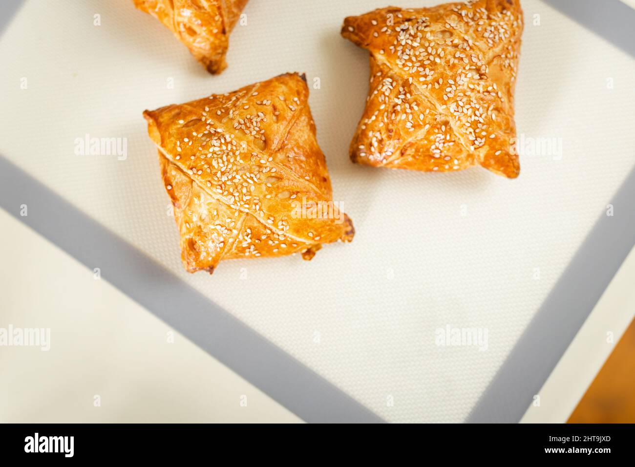 Vista dall'alto della pasta samosa appena sfornata su un tappeto da forno sul tavolo da cucina con spazio copia. Foto Stock