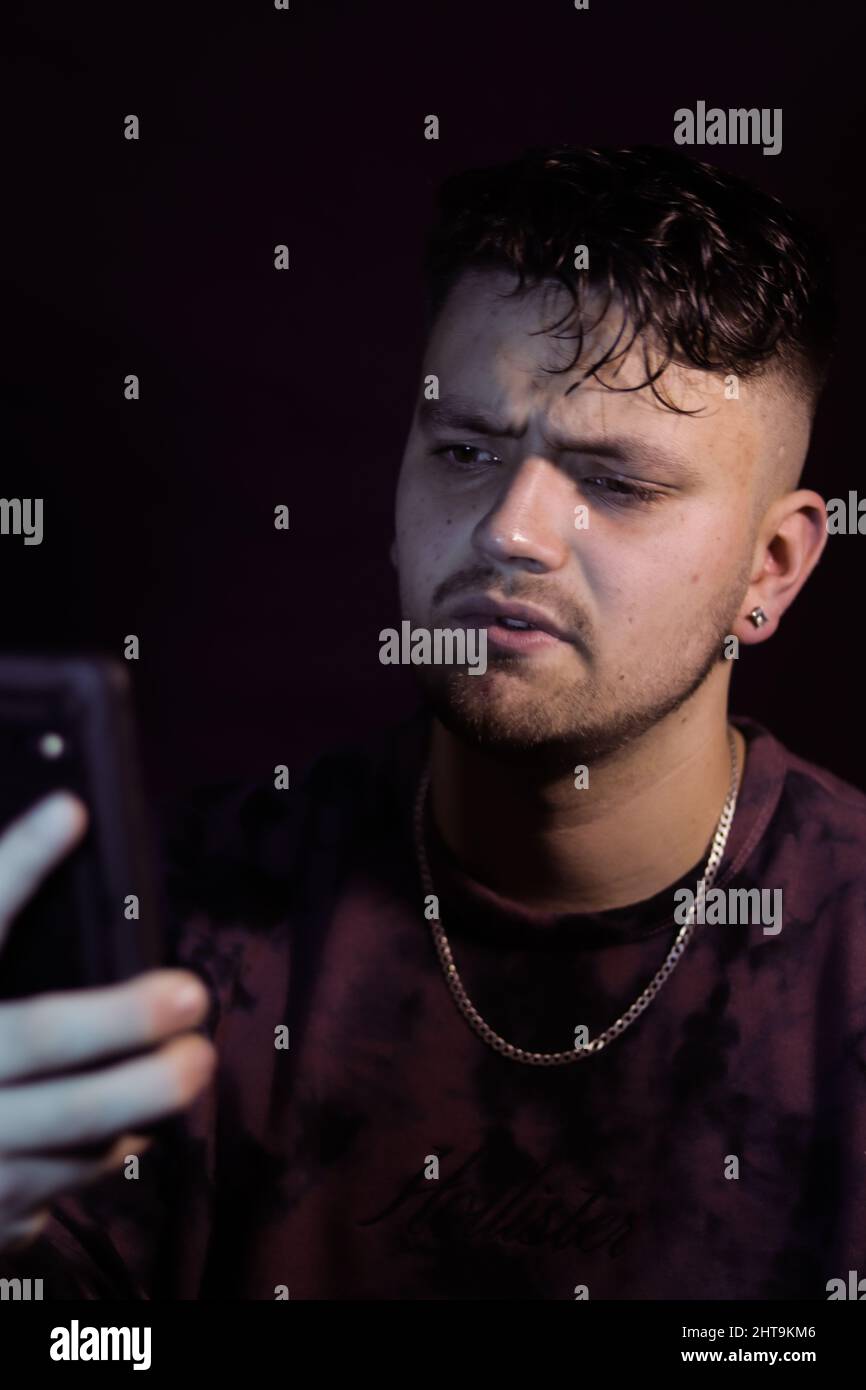 Scatto verticale di un uomo sconvolto che legge notizie sul suo smartphone Foto Stock