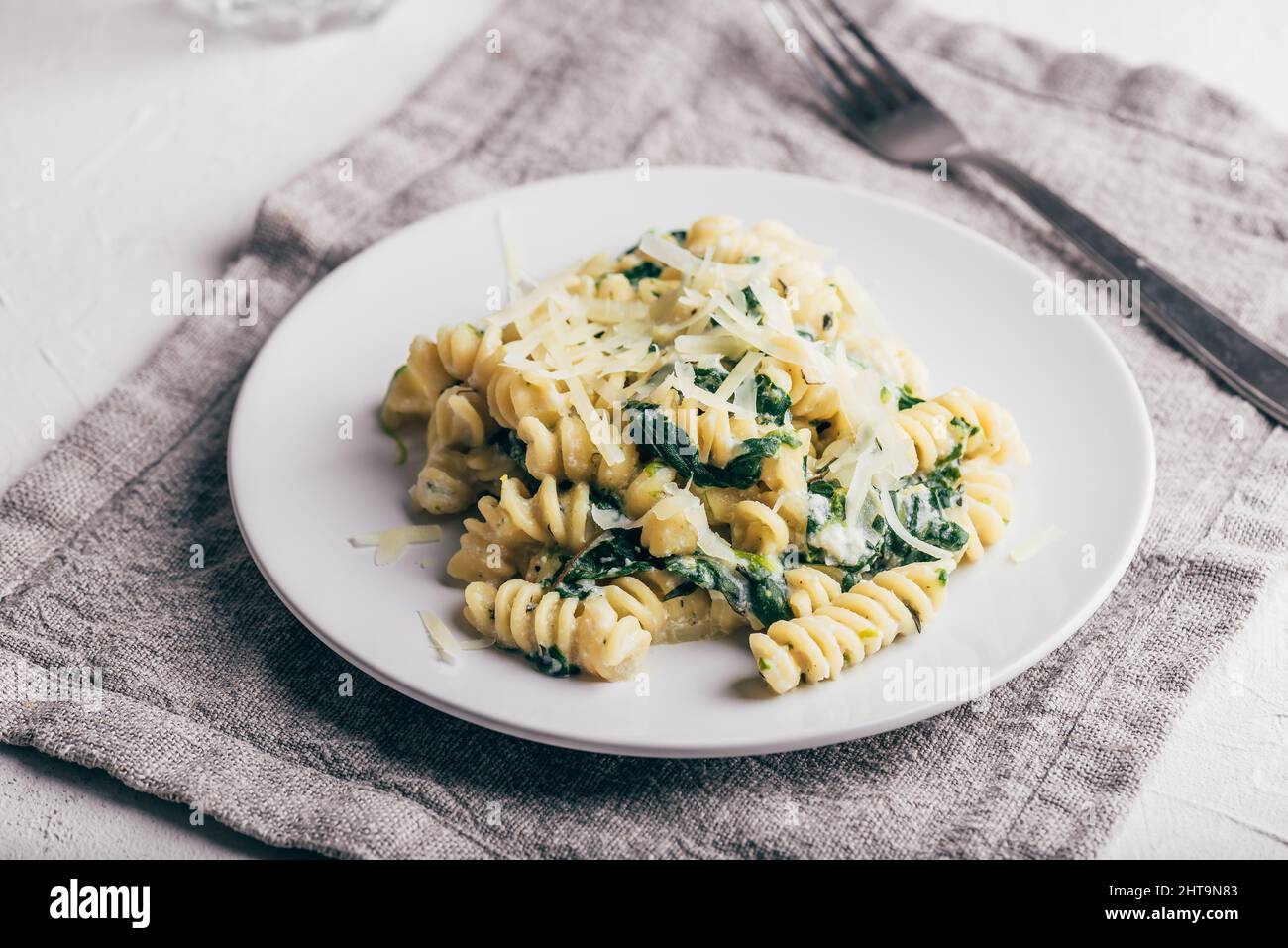 Pasta di fusilli con spinaci e ricotta guarnita con parmigiano grattugiato Formaggio su piatto bianco Foto Stock