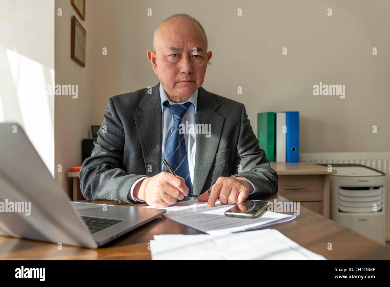 Un dirigente senior che firma un documento in ufficio. Lavoro, concetto di ufficio. Foto Stock