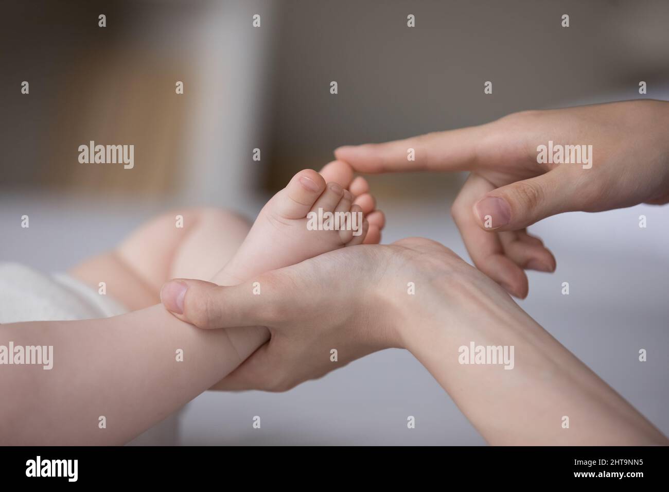 Le mani della mamma toccano i piedi piccoli del bambino, carezzando il capretto Foto Stock