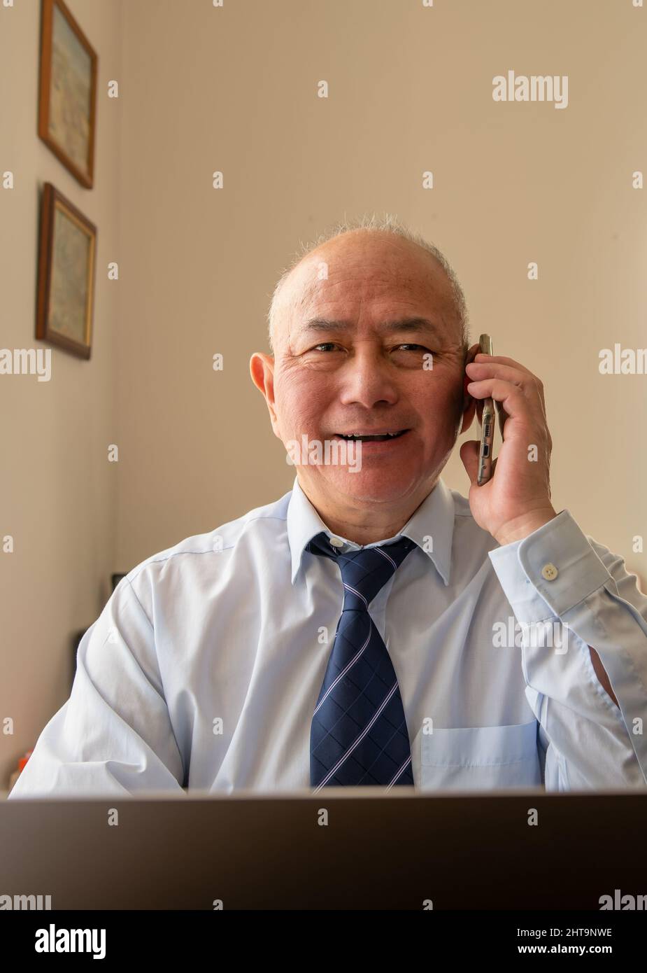 Un anziano anziano impiegato maturo con un sorriso grande dopo aver sentito le buone notizie di un affare grande di affari sul telefono. Foto Stock Un anziano anziano impiegato maturo con un sorriso grande dopo aver sentito le buone notizie di un affare grande di affari sul telefono. Foto Stock