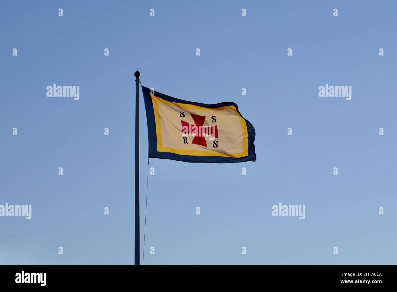 Primo piano della bandiera della Swedish Sea Rescue Society contro un cielo blu senza nuvole Foto Stock