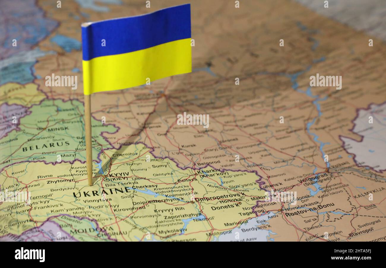 La bandiera Ucraina si è bloccata nel centro del paese. La vicina Russia e la Bielorussia sono importanti. Mappa dell'atlante o del mondo che mostra la posizione del conteggio Foto Stock