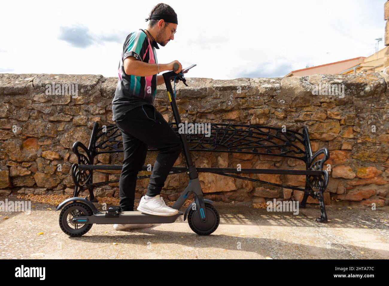 Un giovane turista che guarda il cellulare per il percorso sul suo scooter elettrico Foto Stock
