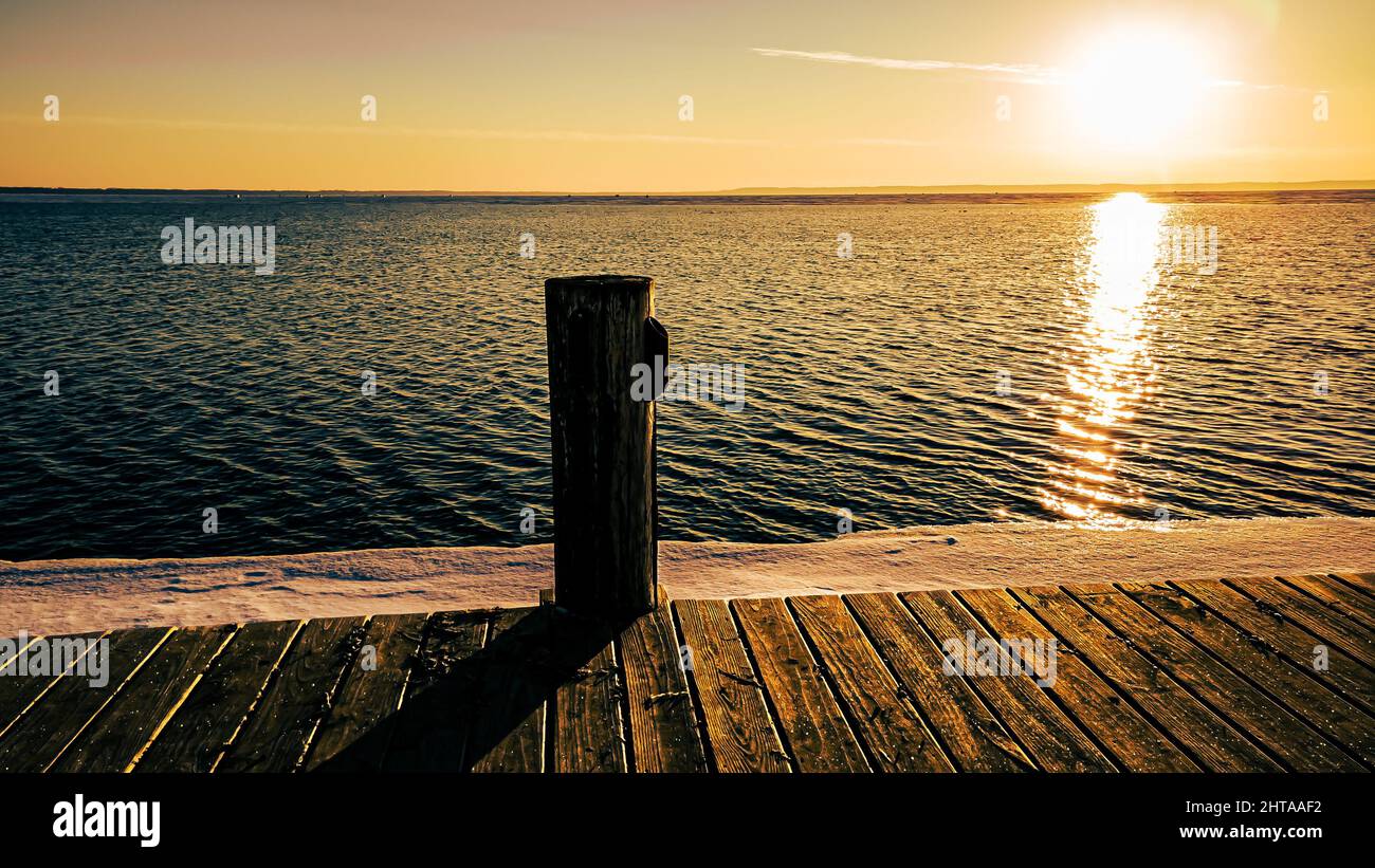 La neve copre la terra con ghiaccio fuori sul lago quando il sole arriva Foto Stock