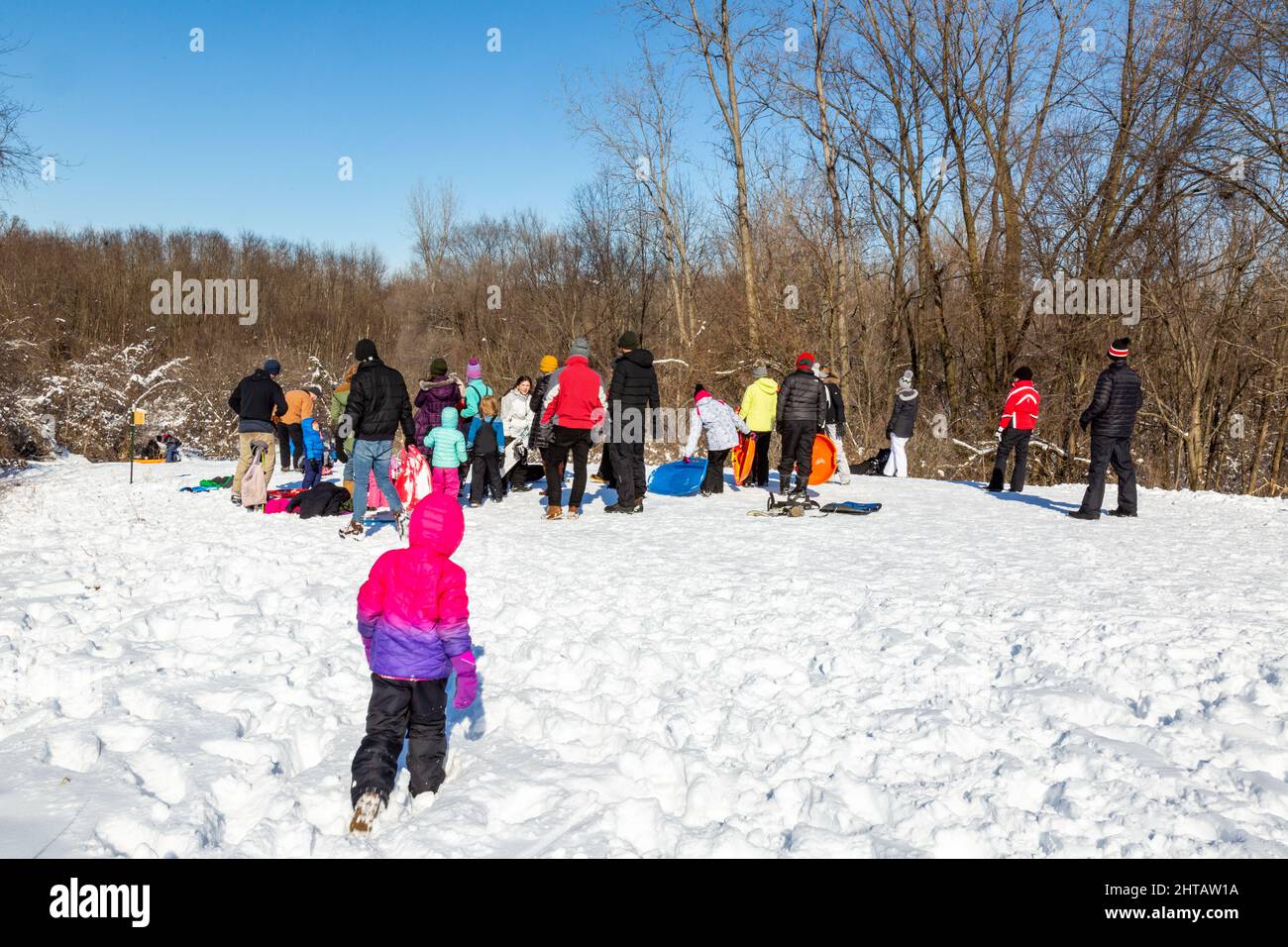 Gli Sledders aspettano il loro turno in cima ad una collina in Metea County Park vicino a Fort Wayne, Indiana, USA. Foto Stock