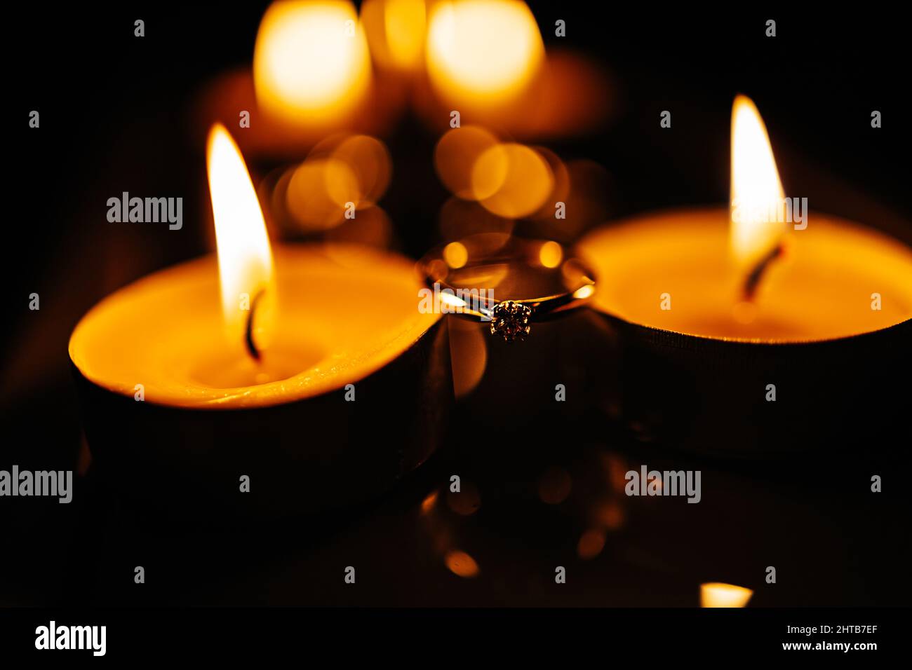 Primo piano di un anello di impegno tra le candele che bruciano Foto Stock