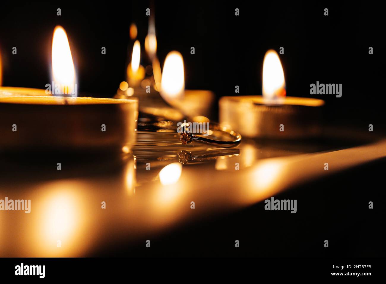 Primo piano di un anello di impegno tra le candele che bruciano Foto Stock