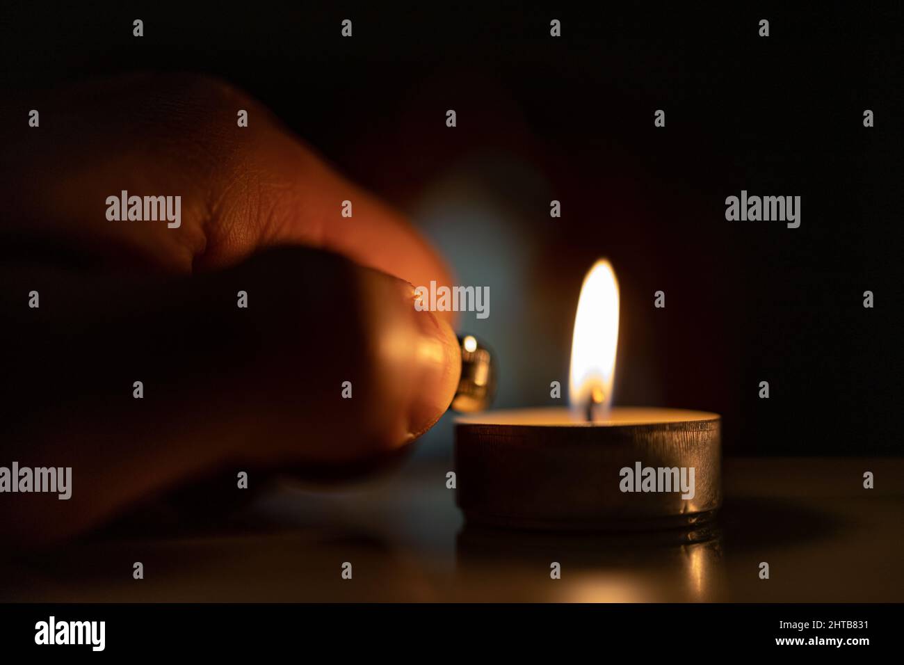 Primo piano di una mano maschile che illumina una candela con un accendino Foto Stock