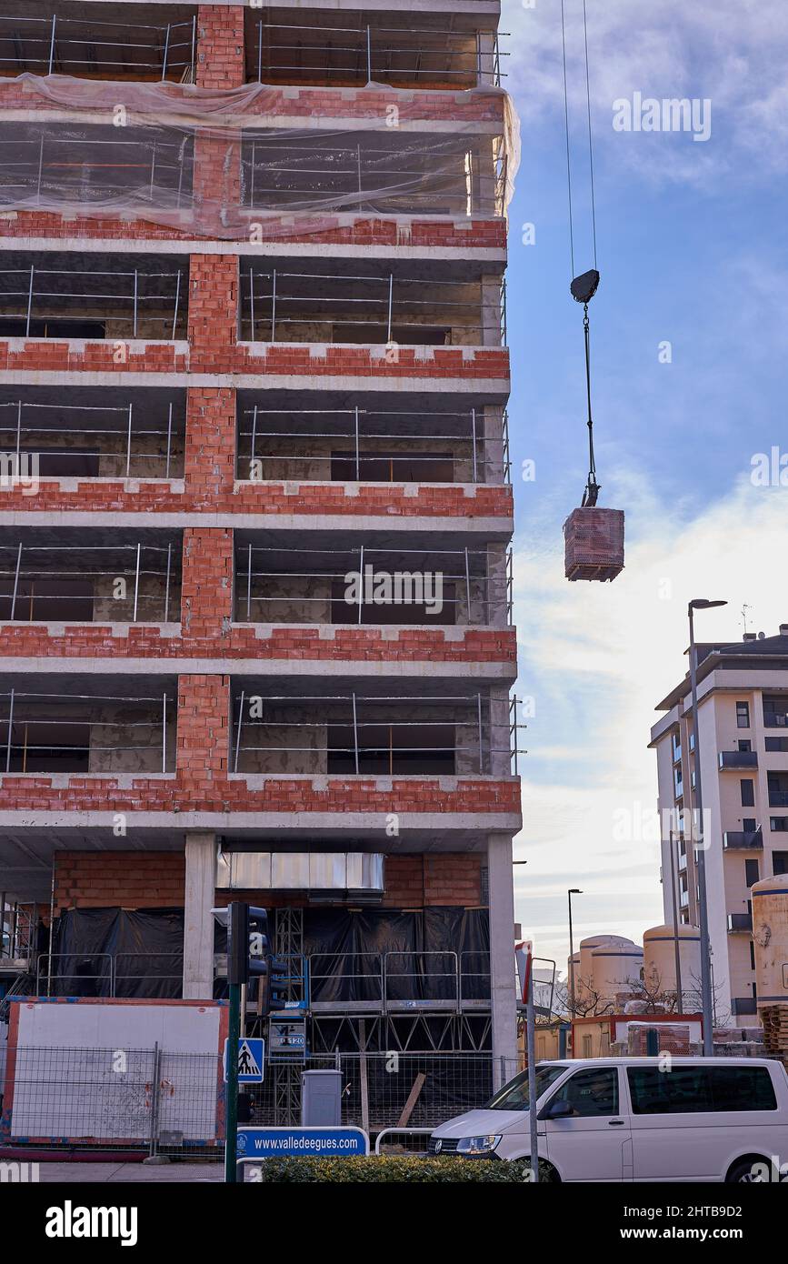 Vista di una gru che lavora al sollevamento di materiali durante la costruzione di una casa di protezione sociale Foto Stock