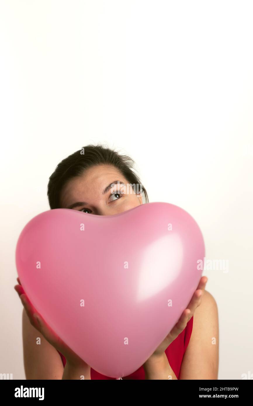 Una donna tiene un pallone gonfiabile a forma di cuore rosa. Compleanno e San Valentino concetto. Vista frontale. Foto Stock