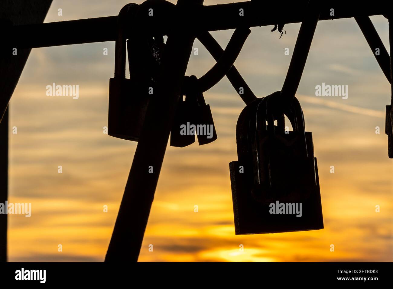 Silhouette di alcune serrature appese su fili metallici sullo sfondo di un tramonto. Foto Stock