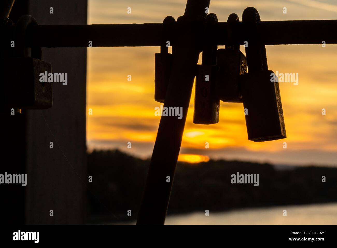 Silhouette di alcune serrature appese su fili metallici sullo sfondo di un tramonto. Foto Stock