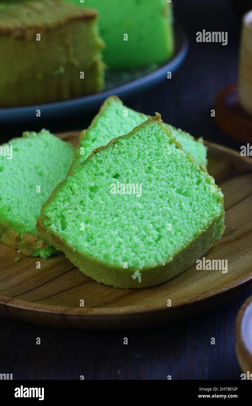 Torta Bolu Pandan o Pandan Chiffon, servita con tè su sfondo di legno scuro. Messa a fuoco selettiva. Foto Stock