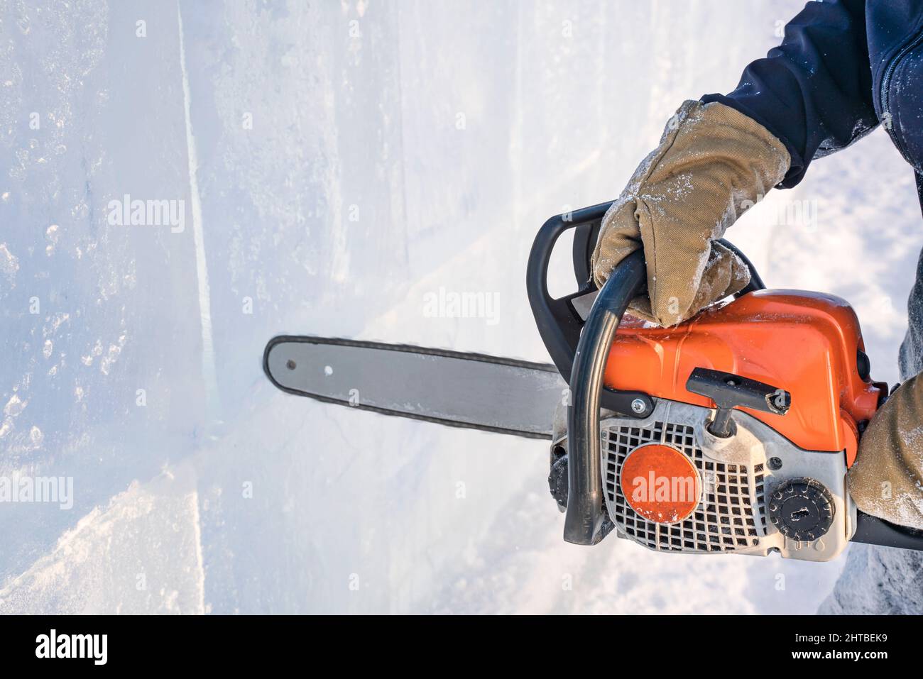 Realizzare sculture di ghiaccio. Un uomo taglia la superficie in un blocco di ghiaccio con una sega a benzina sul lago Baikal. Foto Stock