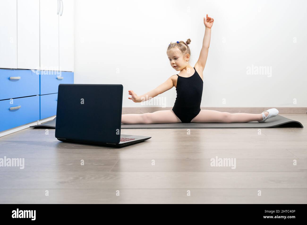ginnastica ritmica online. preschooler ragazza che fa ginnastica ritmica con un allenatore online Foto Stock