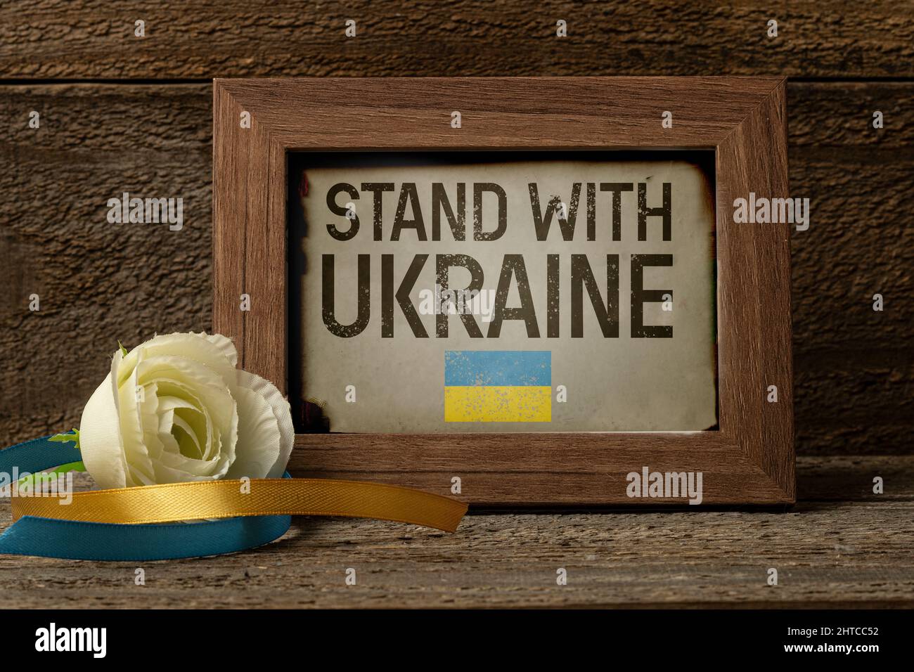 Telaio in legno con testo Stand for Ukraine on ligned table with a white rose and two nasts with ucraine flag color Foto Stock