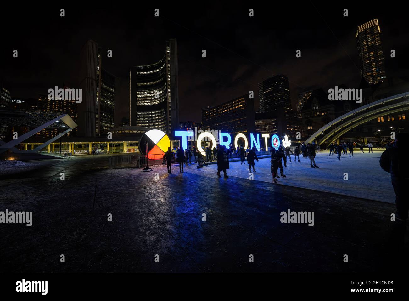 Toronto, Canada. 27th Feb 2022. Un segno 'Toronto' accanto ad una pista di pattinaggio illuminata nei colori della bandiera Ucraina a Piazza Nathan Phillips a Toronto. Dopo l'invasione russa in Ucraina, molti edifici e architetture in tutto il mondo illuminate nei colori della bandiera Ucraina, blu e giallo. Credit: SOPA Images Limited/Alamy Live News Foto Stock