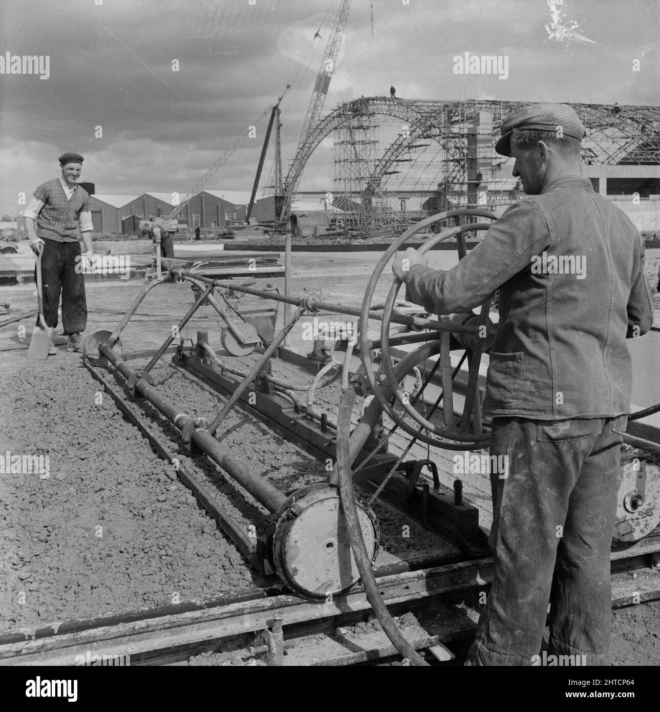 RAF Gaydon, Gaydon, Stratford-on-Avon, Warwickshire, 01/06/1954. Un operaio che opera un compattatore Holman durante la cementazione di una pista o di un grembiule aereo a Gaydon Airfield. I lavori iniziarono alla costruzione di una nuova pista a Gaydon Airfield all'inizio del 1952. A ciò seguì un secondo contratto per la costruzione di oltre 100 edifici Easiform, 23 Huts Nissen e edifici del Ministero dell'aria. Nel 1954, Laing iniziò a costruire due nuovi hangar aerei presso il campo aereo. Foto Stock