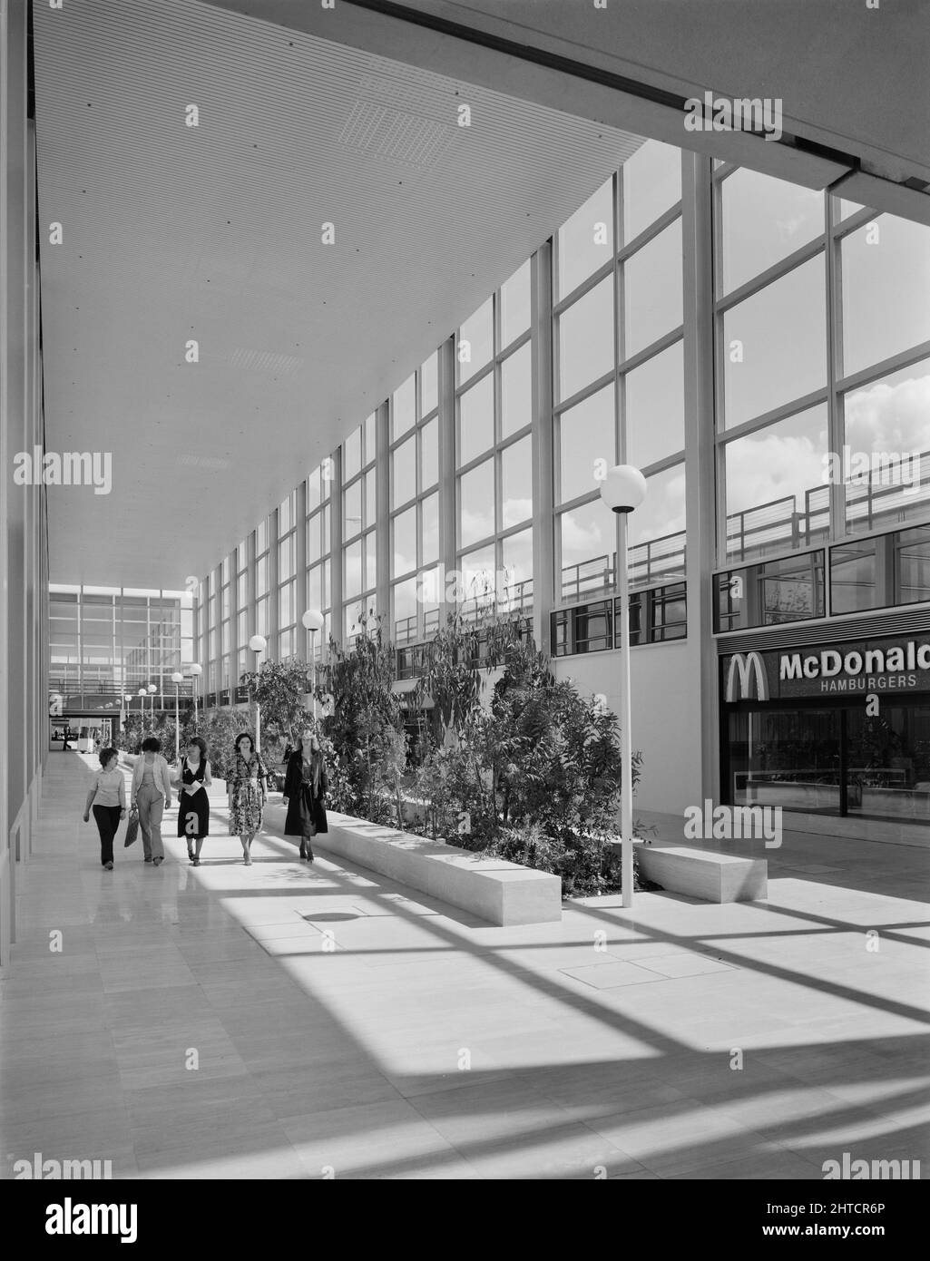 The Shopping Centre, Silbury Boulevard, Milton Keynes, Buckinghamshire, 01/07/1979. Gli amanti dello shopping passeggiando accanto alle piantagioni tropicali in una delle arcate soleggiate del centro commerciale Milton Keynes. Foto Stock