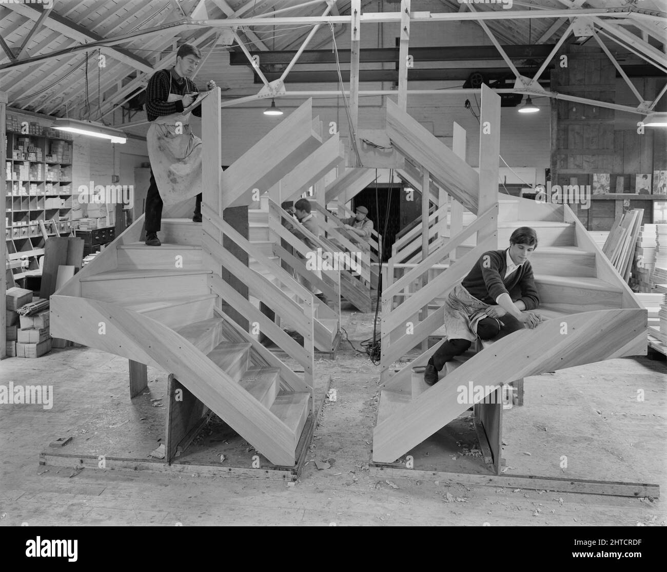 Victoria Joinery Works, Magdalen Street, Earlsfield, Wandsworth, Londra, 25/11/1966. L'interno di Victoria Joinery Works, che mostra un team di uomini al lavoro sulla produzione di scale in legno per 12M abitazioni Jessen. Victoria Joinery Ltd era originariamente parte del gruppo Holloway Brothers, acquisito da John Laing &amp; Son Ltd nel 1964. I lavori si trovavano in via Magdalen a Earlfield, ma da allora sono stati demoliti e la casa occupa ora il sito. La fotografia fa parte di un lotto che mostra le scale fabbricate ai lavori, successivamente installate nelle 12M case di Laing. Foto Stock