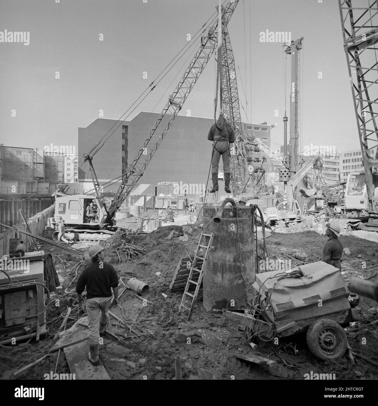 Vintners Place, Upper Thames Street, Queenhitthe, Londra, 01/10/1990. Un lavoratore che viene abbassato mediante gru nell'involucro di acciaio di una delle fondazioni di cumulo alesate a Vintners luogo per intraprendere un'ispezione. Laing ha sottoscritto il contratto di gestione &#XA3;79m per la costruzione di un ufficio di alta qualità 37.000sqm a Vintners luogo tra marzo 1989 e dicembre 1992. I lavori in loco sono iniziati nel giugno 1989 con la demolizione di 10 edifici, tra cui Vintry House e Kennett Wharf, sul lungofiume. La fa&#xe7;ade di Tamigi House lungo Queen Street Place è stato conservato e incorporato Foto Stock