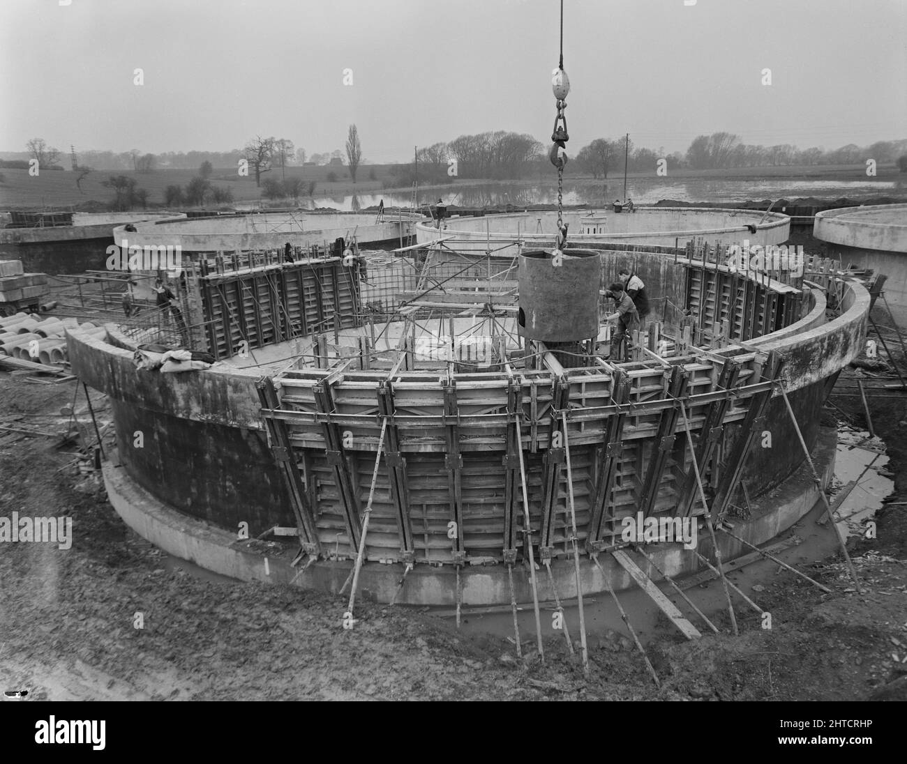 Wanlip Sewage Works, Wanlip, Charnwood, Leicestershire, 31/03/1960. Lavoratori che concretizza una sezione di muro nel serbatoio di separazione No.4 a Wanlip Sewage Works. I lavori di costruzione dei Wanlip Sewage Works sono iniziati nel dicembre 1958. L'intero sito doveva essere inumidito con il cumino di fogli prima dello scavo, a causa della vicinanza del fiume Soar. Il contratto iniziale comprendeva la costruzione di tre unità di vasca di aerazione con 36 tasche, e di una vasca di aerazione con 18 tasche. In ciascuna unità erano incorporati anche quattro serbatoi di separazione. Un locale pompe per fanghi di ritorno, un'uscita degli effluenti, tubazioni e un perma Foto Stock