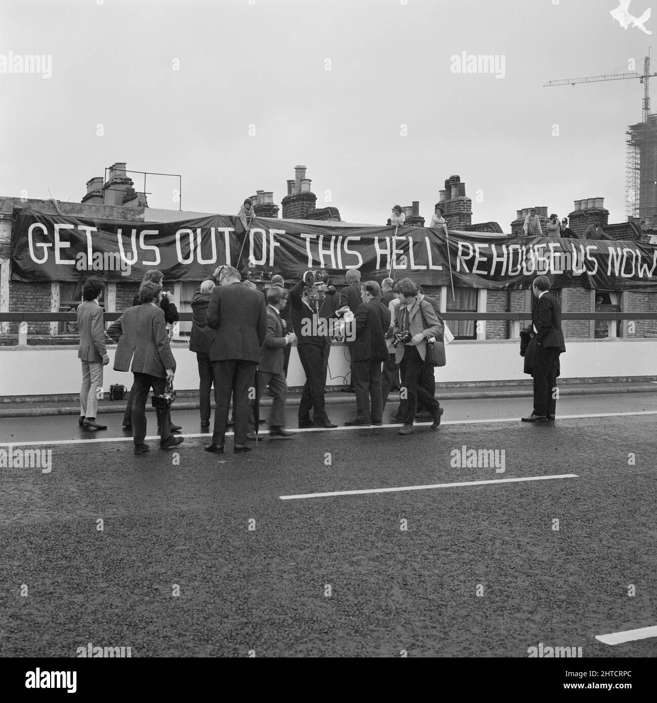 Westway Flyover, A40, Kensington e Chelsea, Londra, 28/07/1970. Michael Heseltine e un gruppo di giornalisti all'apertura del Westway Flyover, con un banner di protesta drappeggiato sullo sfondo. Michael Heseltine era allora segretario parlamentare al Ministero dei Trasporti e depublizzò il Ministro John Peyton per tagliare il nastro per l'apertura del Flyover Westway. Acklam Road è stata al centro delle proteste contro il Westway da parte dei residenti locali. Le case lungo un lato della strada erano state demolite per far posto al cavalcavia e ad una reception tenuta in precedenza quel giorno al Signore&# Foto Stock