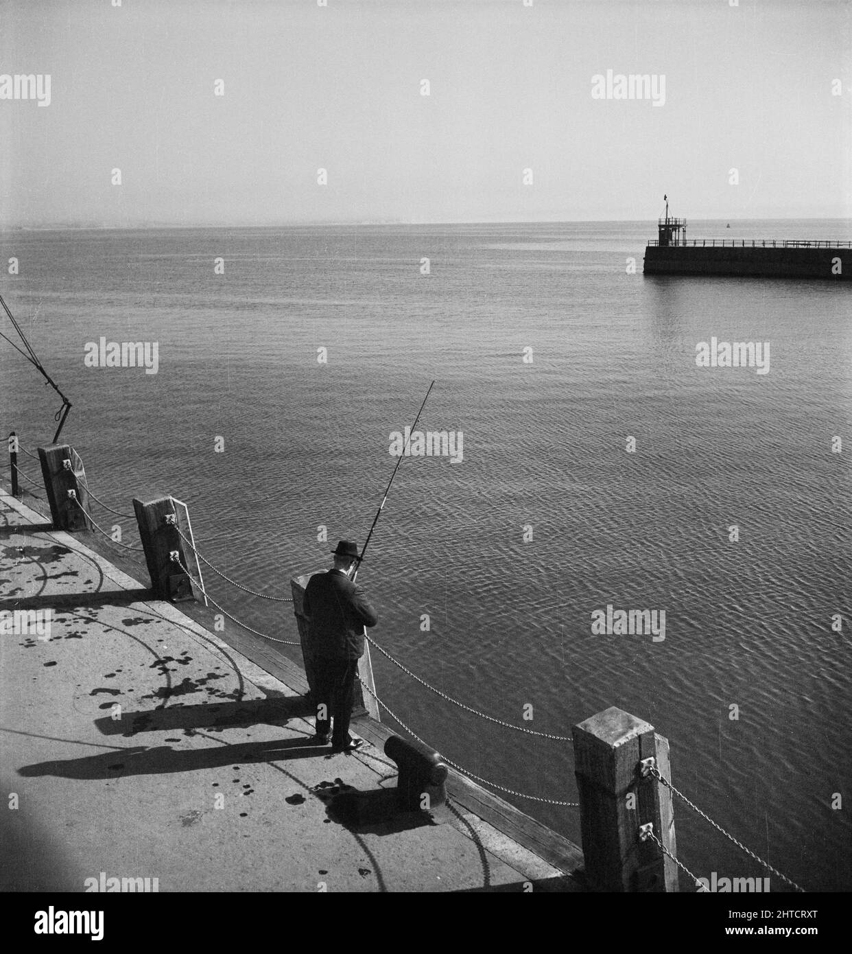 Weymouth, Weymouth e Portland, Dorset, probabilmente giu 1948. Guardando verso il basso un uomo che pesca dalla banchina del porto di Weymouth. Questa foto è stata scattata durante una gita del personale di Laing a Weymouth. Sebbene il fotografo non abbia registrato alcuna data, è noto che nel giugno 1948 si è svolta una gita del personale. Foto Stock