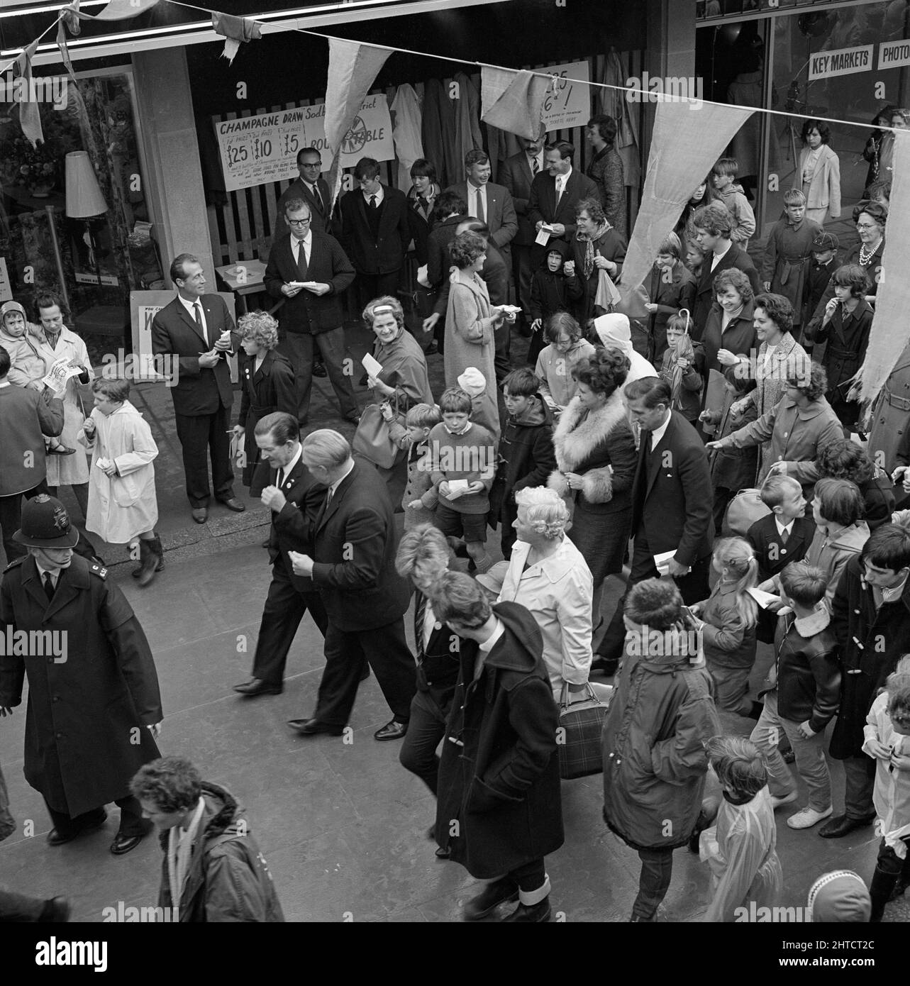 Yate Shopping Centre, Yate, South Gloucestershire, 25/09/1965. Una folla che cammina lungo un quartiere allo Yate Shopping Centre per la sua apertura ufficiale, mostrando l'attrice Pat Phoenix e radio e TV personalità Ted Ray tra il gruppo. Il centro commerciale Yate è stato progettato dagli architetti Stone, Toms and Partners ed è stato costruito da Laing. Fu costruito per servire una popolazione in crescita ed era un legame tra il vecchio villaggio e la nuova città con le sue case moderne. Il centro commerciale era costituito da quattro ampi quartieri commerciali collegati da un centro di corte, che ospitava quattro banche, un supermercato e un negozio Woolworths Foto Stock