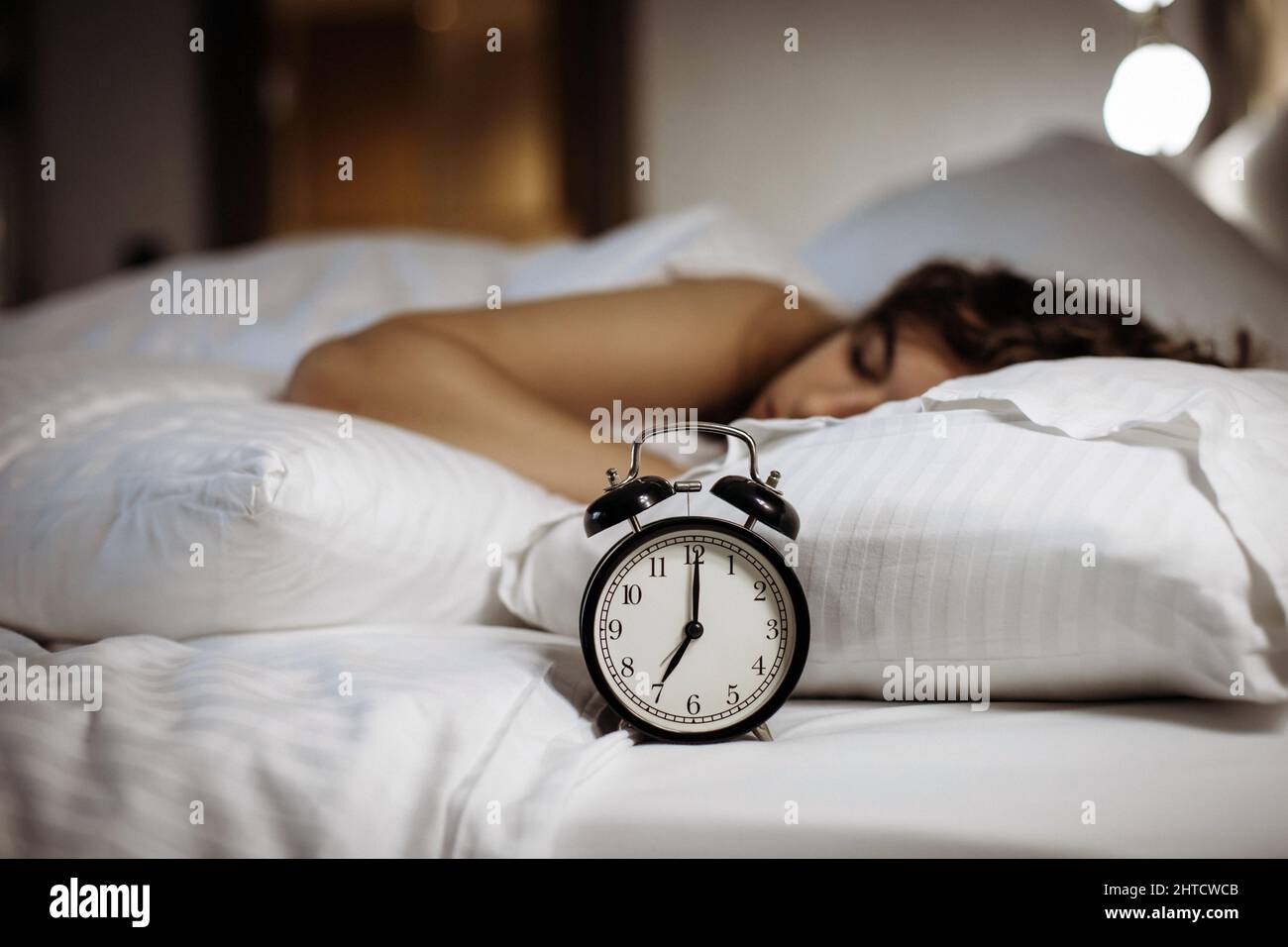 Sveglia sul letto con la donna che dorme dietro Foto stock - Alamy