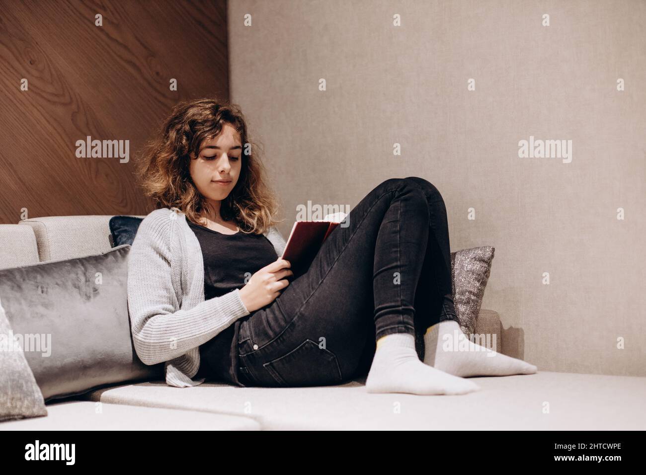 Adolescente ragazza lettura libro sul divano a casa Foto Stock