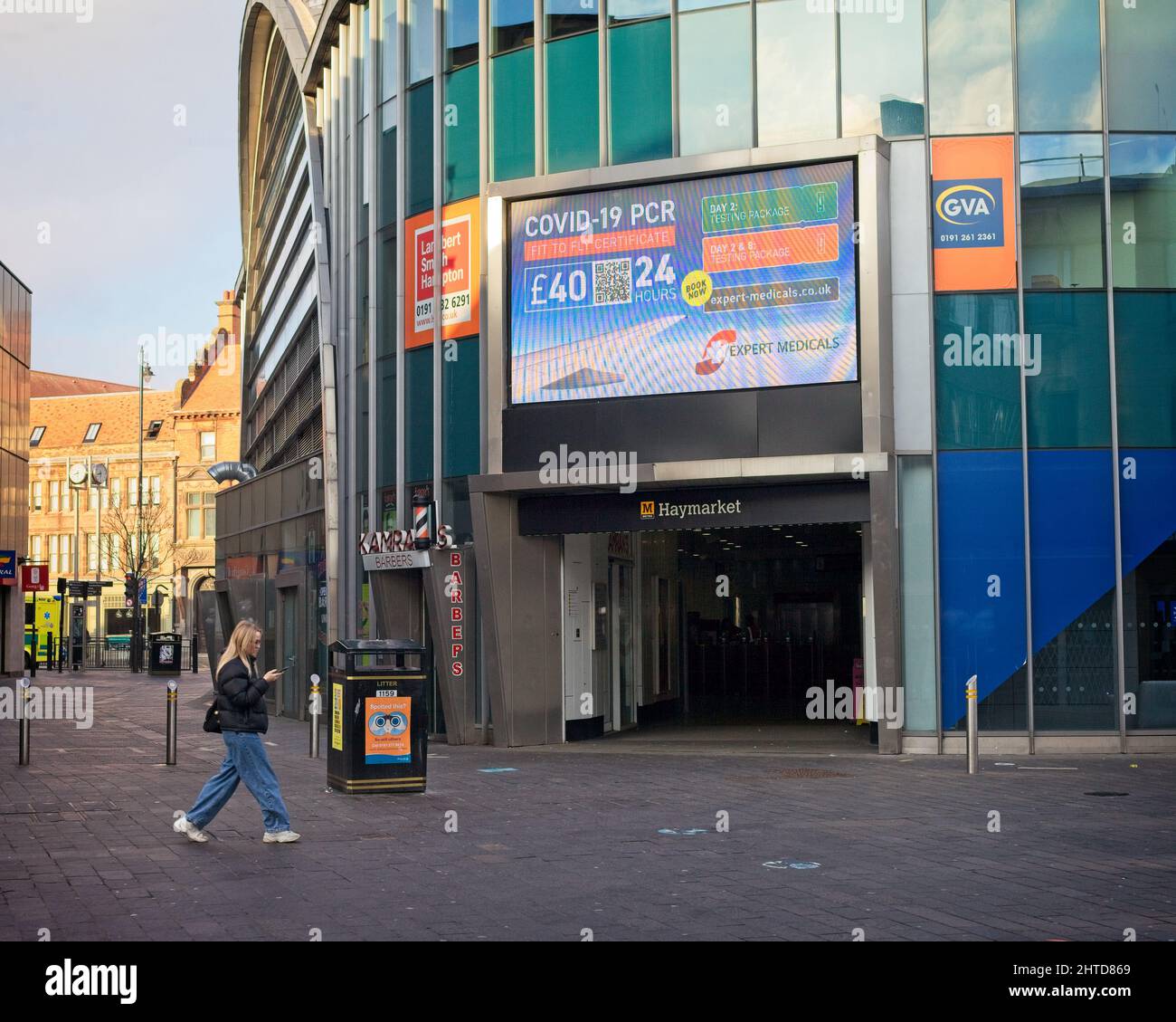 Una giovane donna controlla il suo telefono mentre cammina nel centro di Newcastle vicino alla stazione della metropolitana Haymarket. Foto Stock